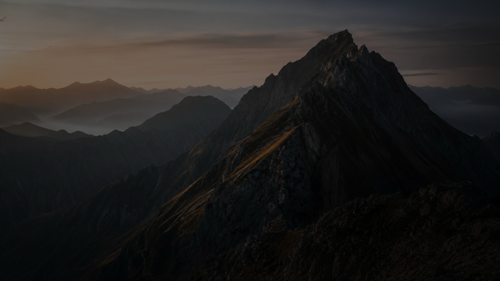 An alpine ridge rising above layers of distant mountains